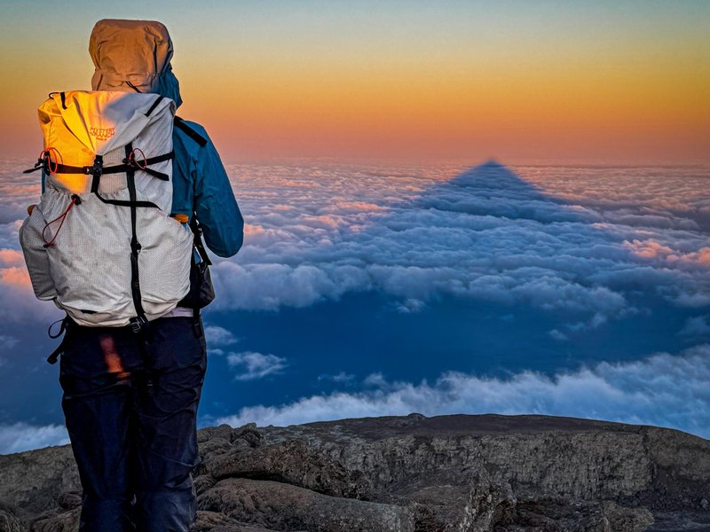 Sunrise and the mountain's shadow stretching across the clouds — pure magic after a night climb.